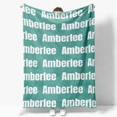 Mint green throw blanket with repeated white text ’amberlee’ design.