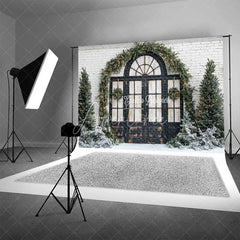 Aperturee - Aperturee Christmas Front Door Backdrop Black Arched Window Wreath Pine Trees Lights Snow White Brick Background